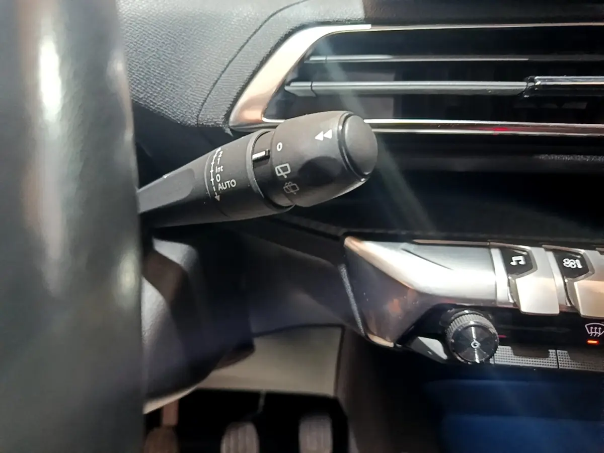 Gros plan sur la commande d’essuie-glace à gauche du volant dans l’habitacle noir du Peugeot 3008 2022.