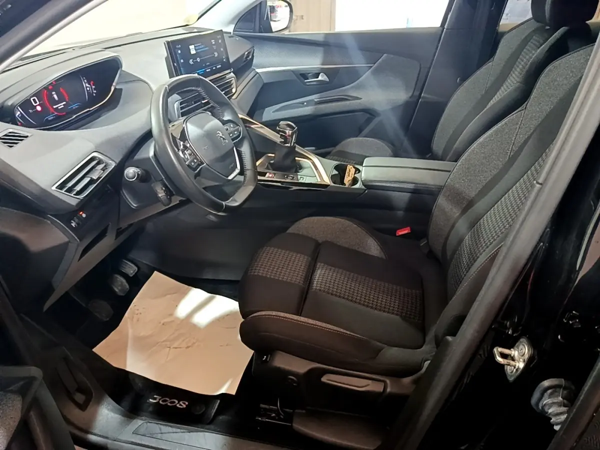 Vue intérieure côté conducteur du Peugeot 3008 noir 2022, avec tableau de bord numérique et sièges tissu bicolores.