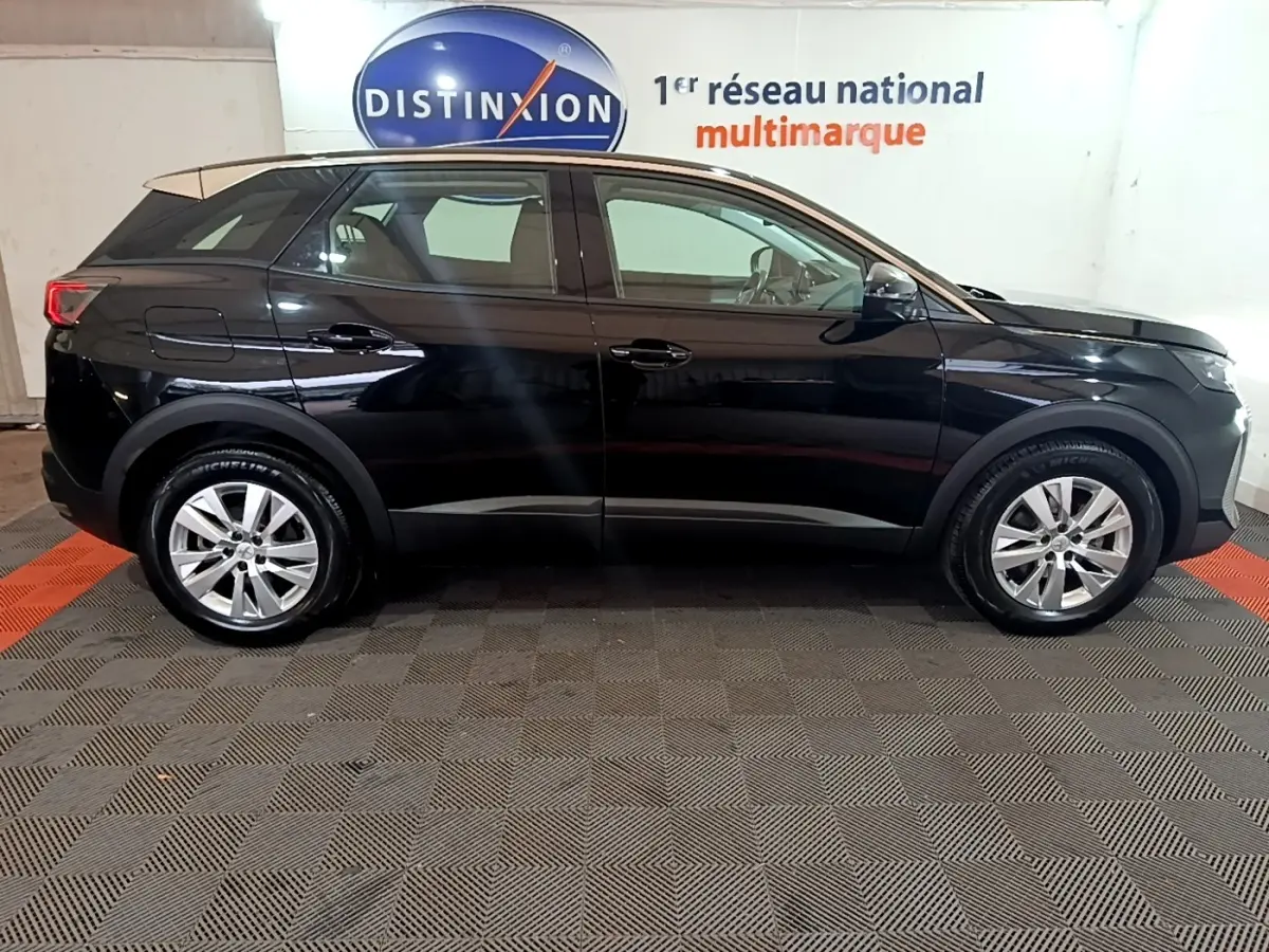 Vue latérale droite d'un Peugeot 3008 noir 2022 stationné en intérieur avec jantes alliage et toit beige clair.