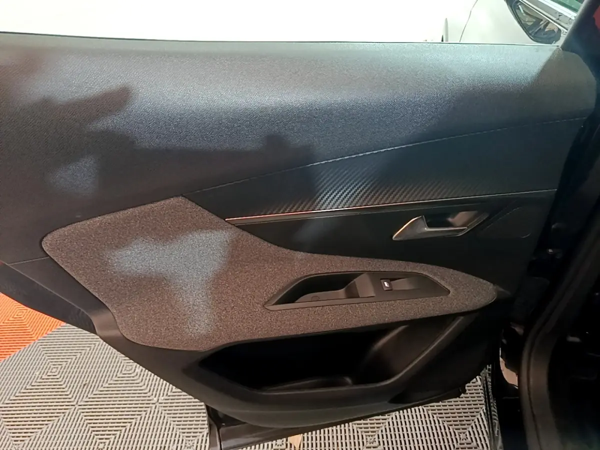 Vue intérieure du panneau de porte côté gauche du Peugeot 3008 noir, avec insert texturé et poignée métallique.