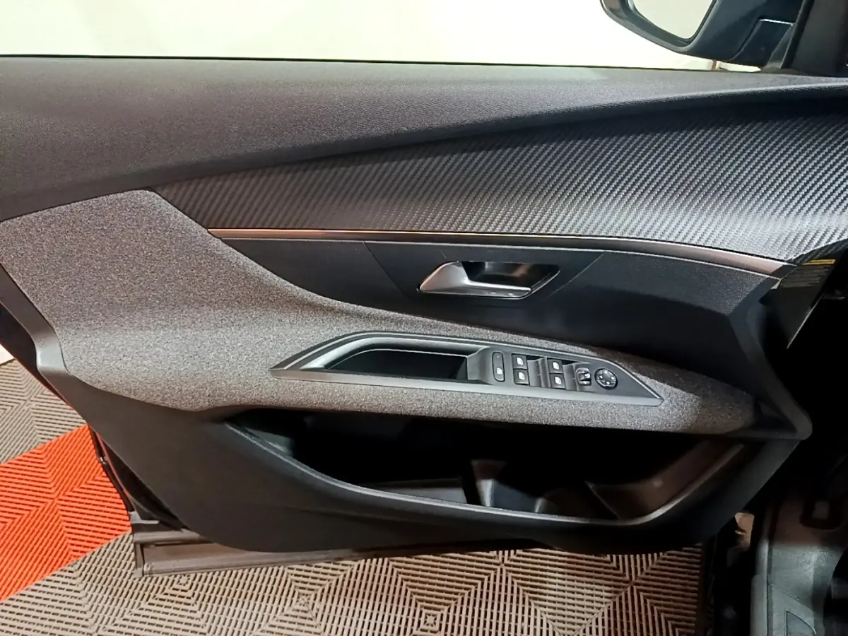 Vue intérieure côté gauche de la porte avant noire du Peugeot 3008 2022 avec commandes de vitres et poignée chrome.