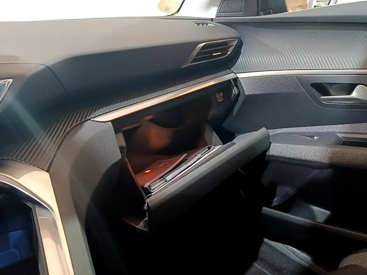 Vue intérieure côté passager du tableau de bord noir du Peugeot 3008 2022 avec boîte à gants ouverte et détails de la garniture.