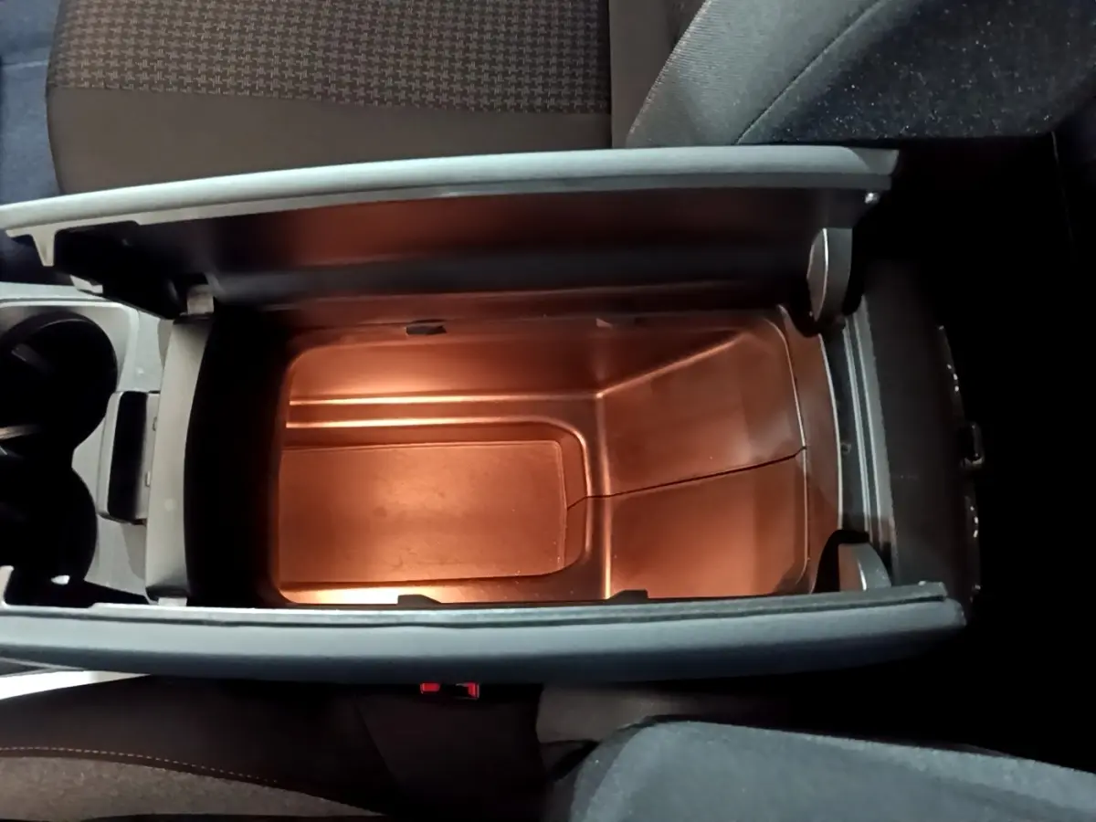 Vue plongeante sur le rangement central ouvert du Peugeot 3008 noir, mettant en valeur l'intérieur spacieux et éclairé.