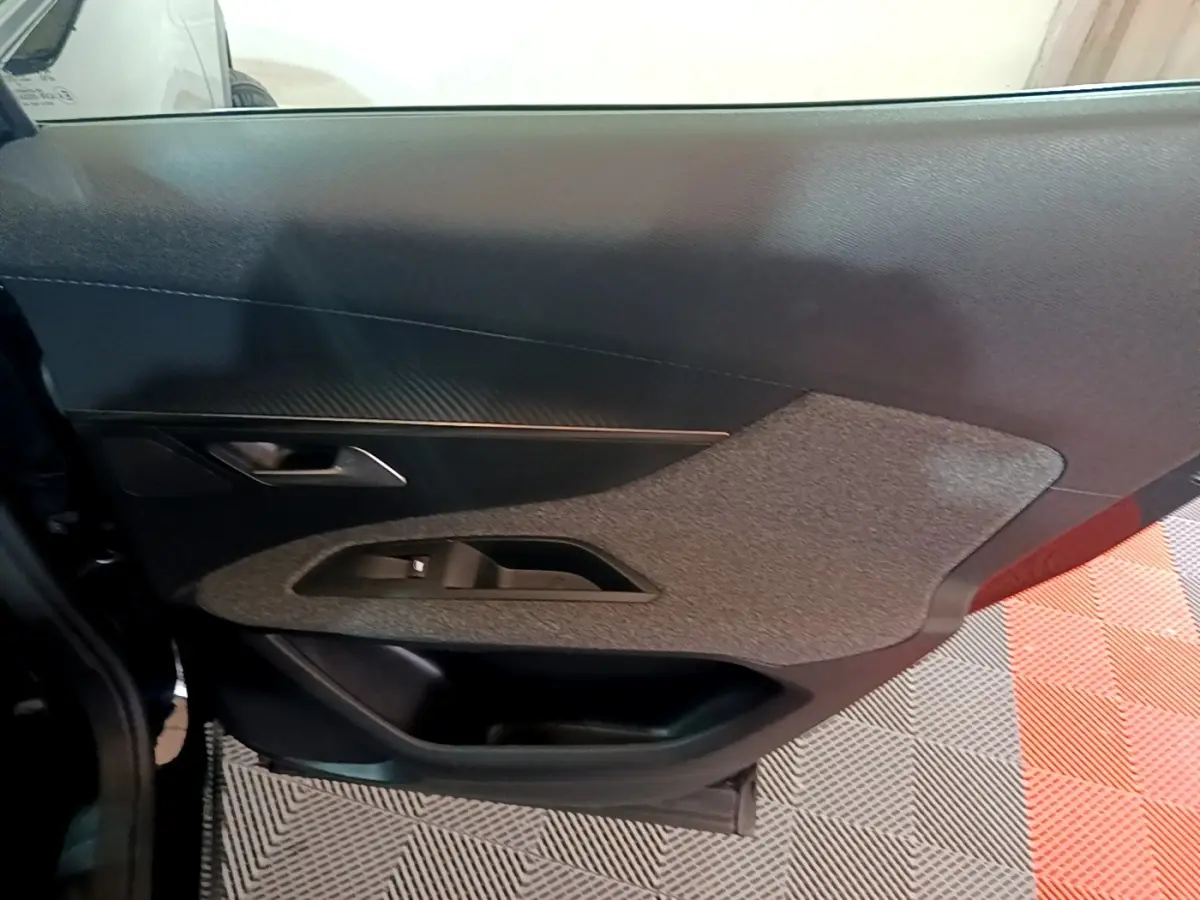 Vue intérieure du panneau de porte côté gauche d'une Peugeot 3008 noir, avec insert tissu gris et commande de lève-vitre.
