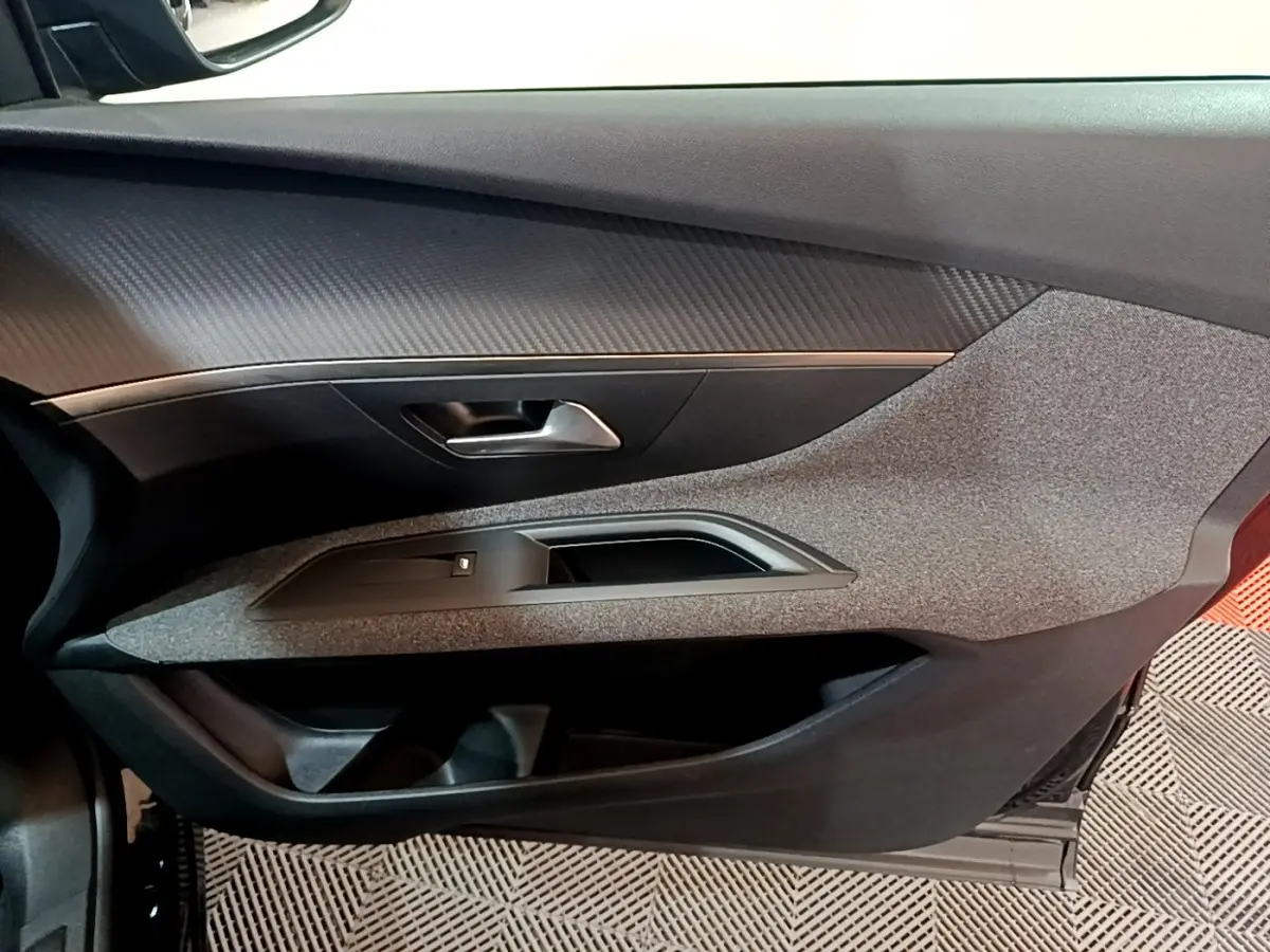 Vue intérieure côté gauche de la porte avant noire du Peugeot 3008 avec habillage texturé et poignée métallique.