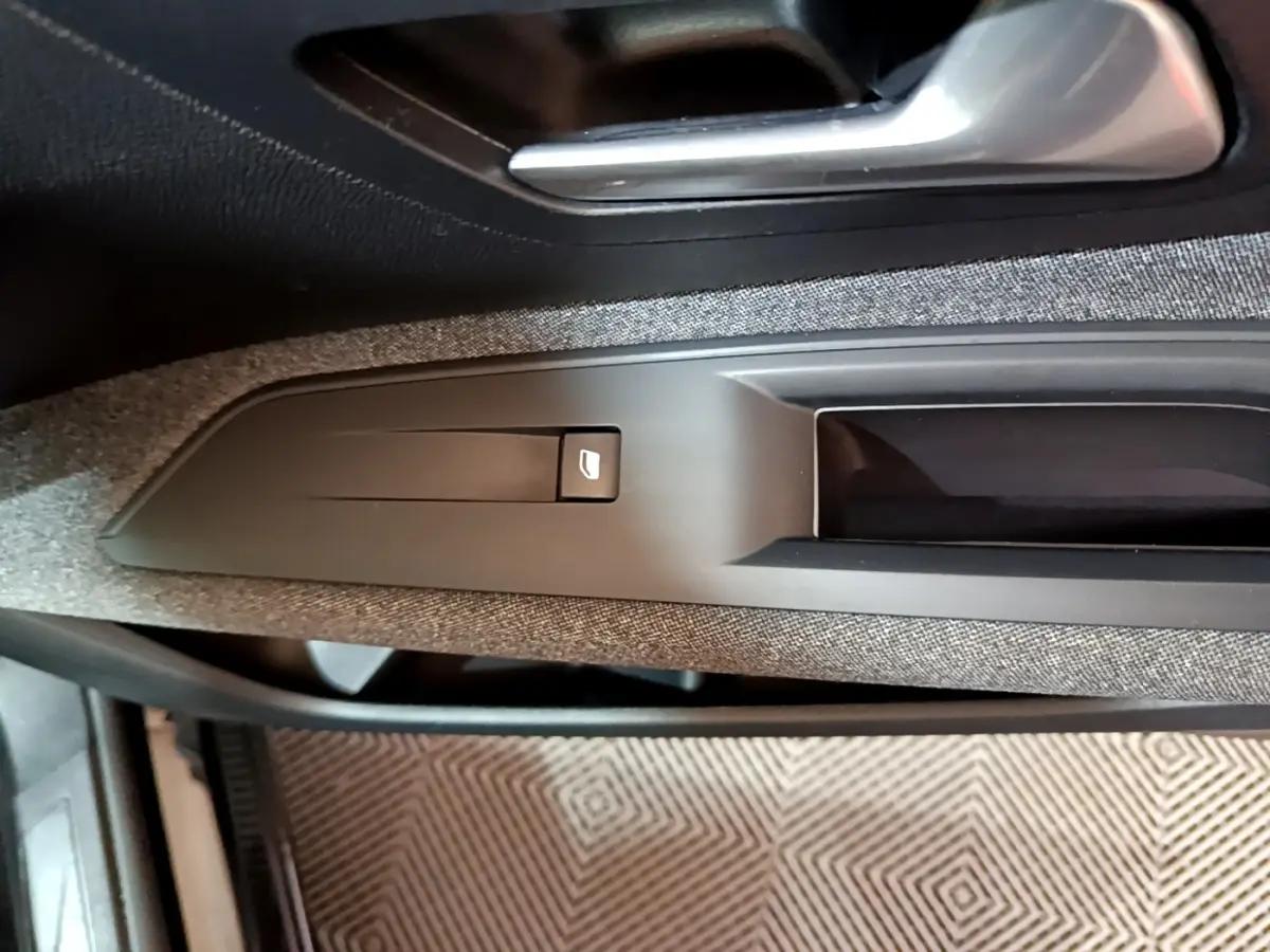 Détail de la commande de lève-vitre côté gauche sur la porte intérieure tissu gris du Peugeot 3008 noir 2022.