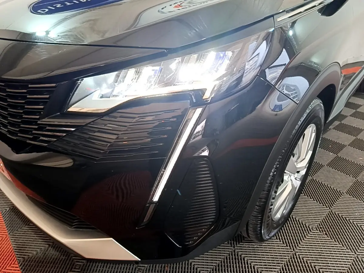 Gros plan sur l'avant droit noir brillant du Peugeot 3008 avec phare LED allumé et jante visible.