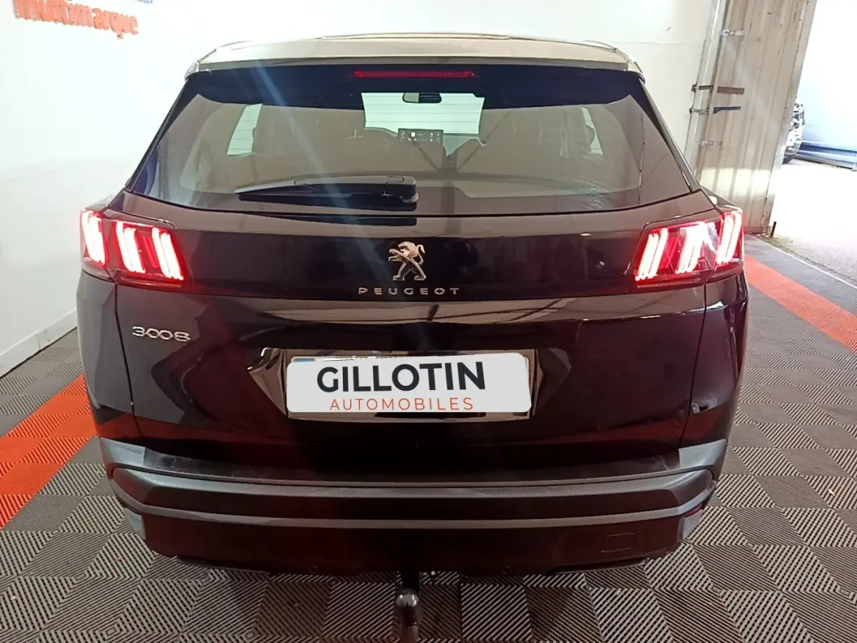 Vue arrière d'un Peugeot 3008 noir 2022 avec feux arrière allumés et attelage visible en intérieur showroom.