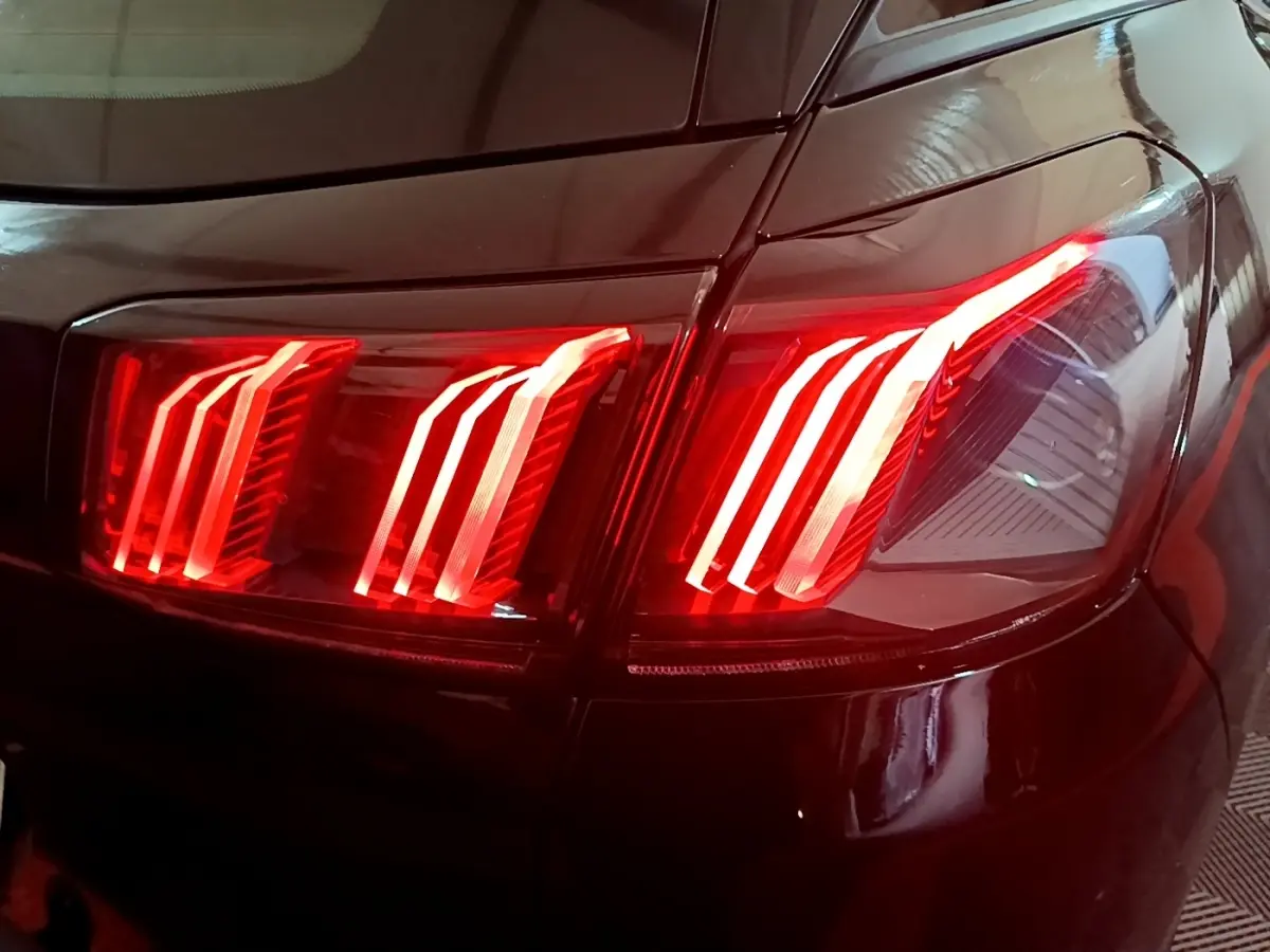 Gros plan sur le feu arrière droit rouge allumé d’un Peugeot 3008 noir, version BlueHDi 130 S&S Active Pack 2022.