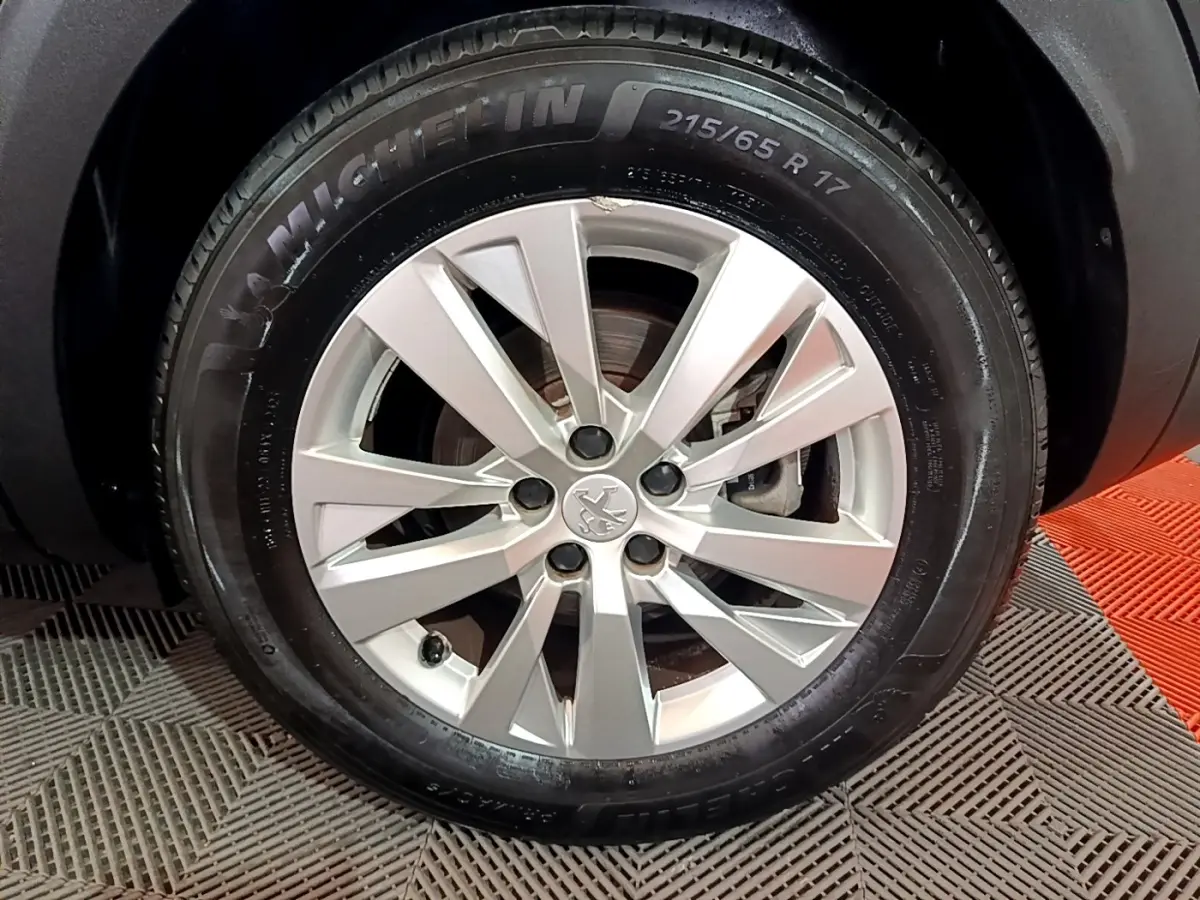 Gros plan sur la roue avant droite d’un Peugeot 3008 noir, jante alliage argentée et pneu Michelin 215/65 R17.