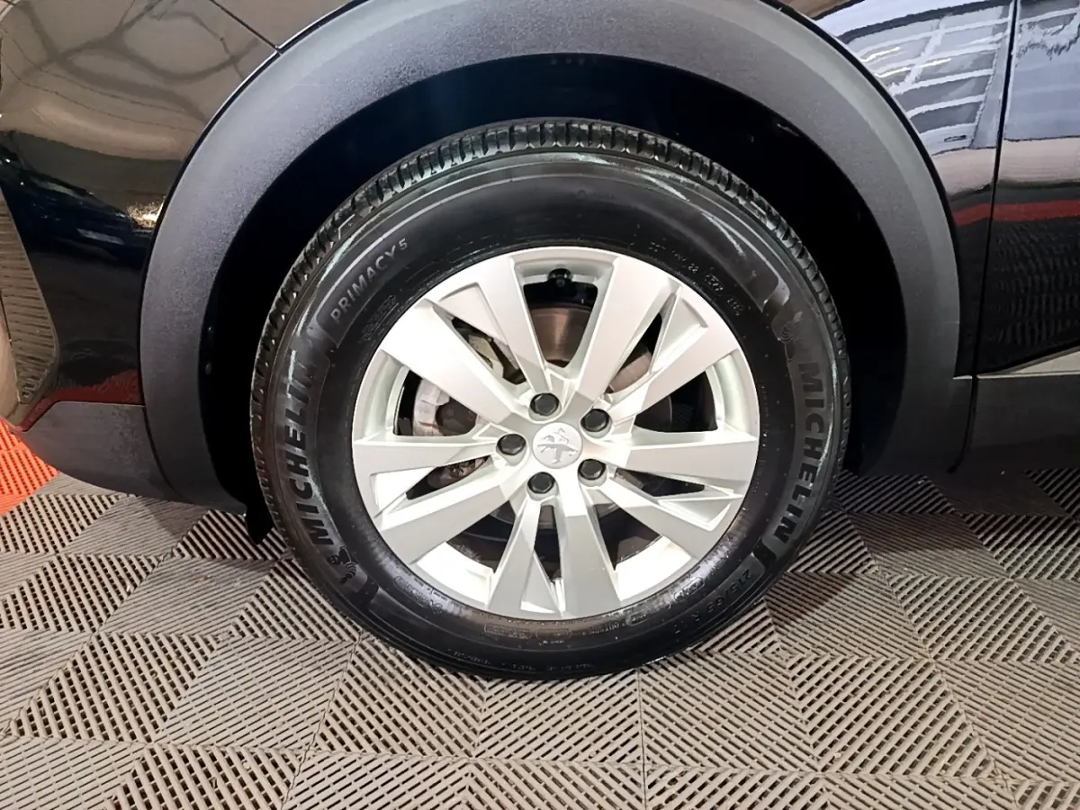 Gros plan sur la roue avant droite du Peugeot 3008 noir, mettant en valeur la jante alliage et le pneu Michelin.