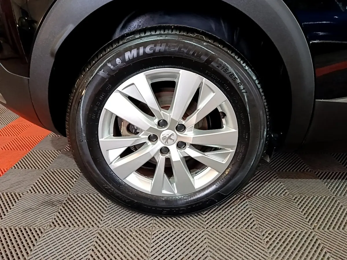 Gros plan sur la roue avant droite d’un Peugeot 3008 noir avec jante alliage et pneu Michelin.