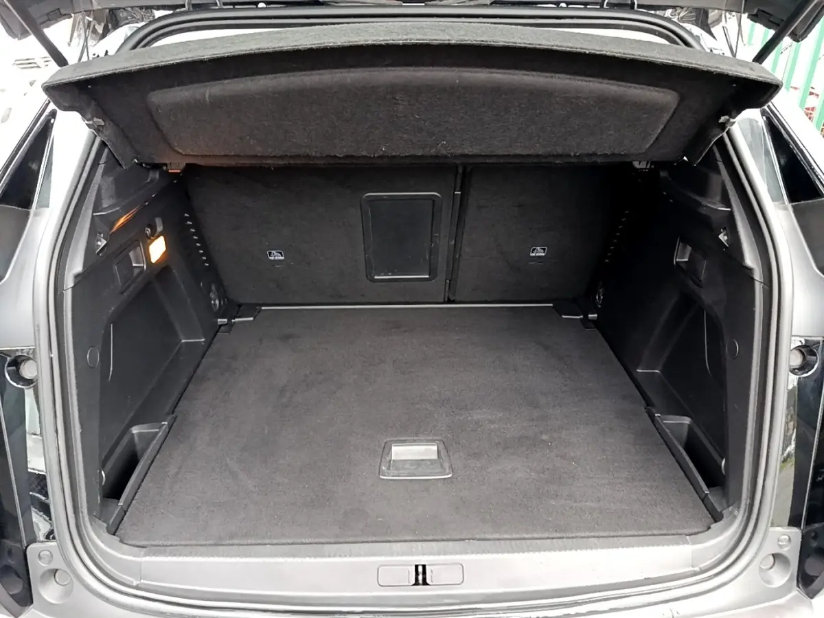 Coffre ouvert vu de l'arrière d'un Peugeot 3008 noir, montrant un espace de chargement propre et spacieux.