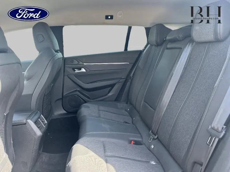 Vue intérieure arrière côté droit montrant les sièges en tissu gris et les détails de la porte d'une Peugeot 508 SW 2021.