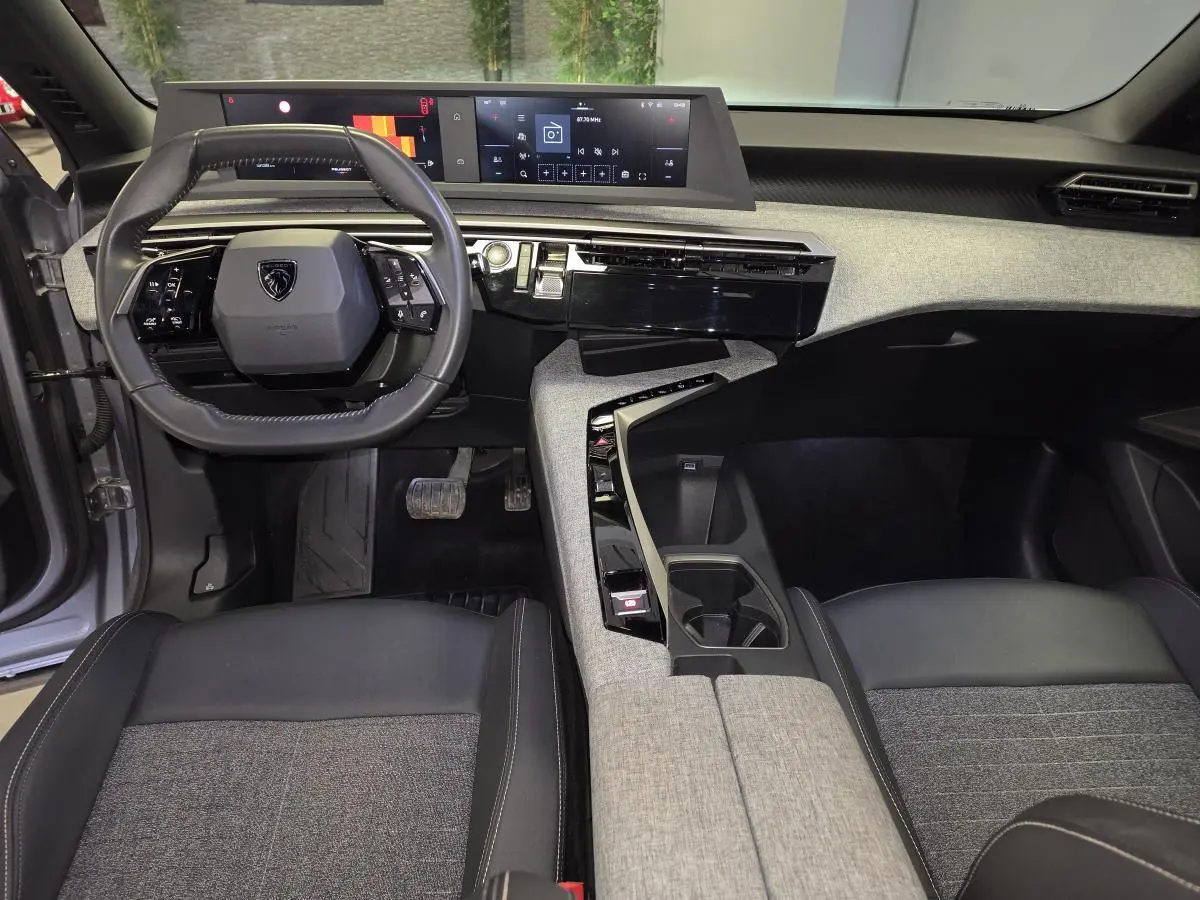 Intérieur avant du Peugeot 3008 gris, avec tableau de bord tissu chiné, volant compact et double écran HD panoramique.