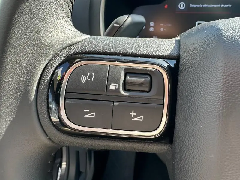 Gros plan sur les commandes de volume et téléphone au volant du Citroën C5 Aircross 1.2 Hybride gris Platinium.