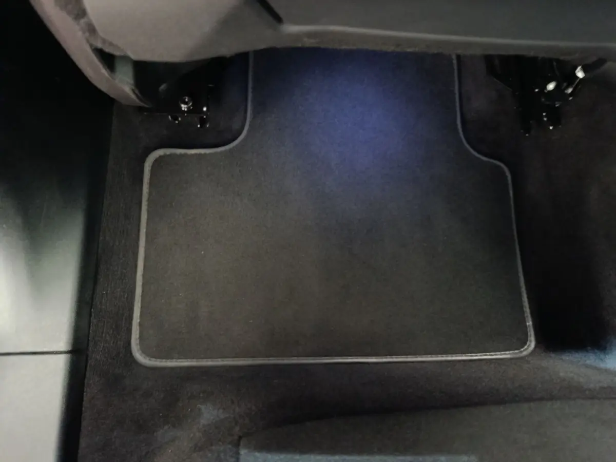 Vue rapprochée du tapis de sol noir sous le siège avant droit d'un Link & Co 01 hybride rechargeable bleu 2022.