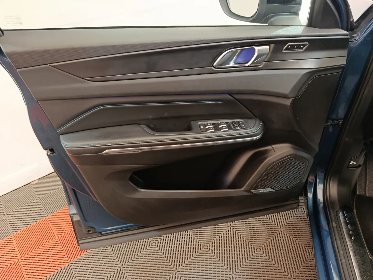 Vue intérieure côté gauche de la porte avant bleu du Link & Co 01 avec commandes électriques et haut-parleur intégré.