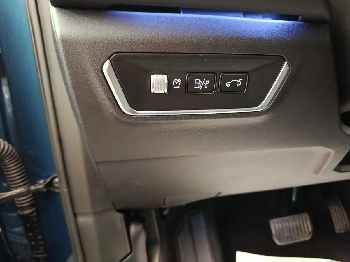 Vue rapprochée des commandes sur la partie inférieure gauche du tableau de bord d’un Link & Co 01 bleu 2022 hybride rechargeable.