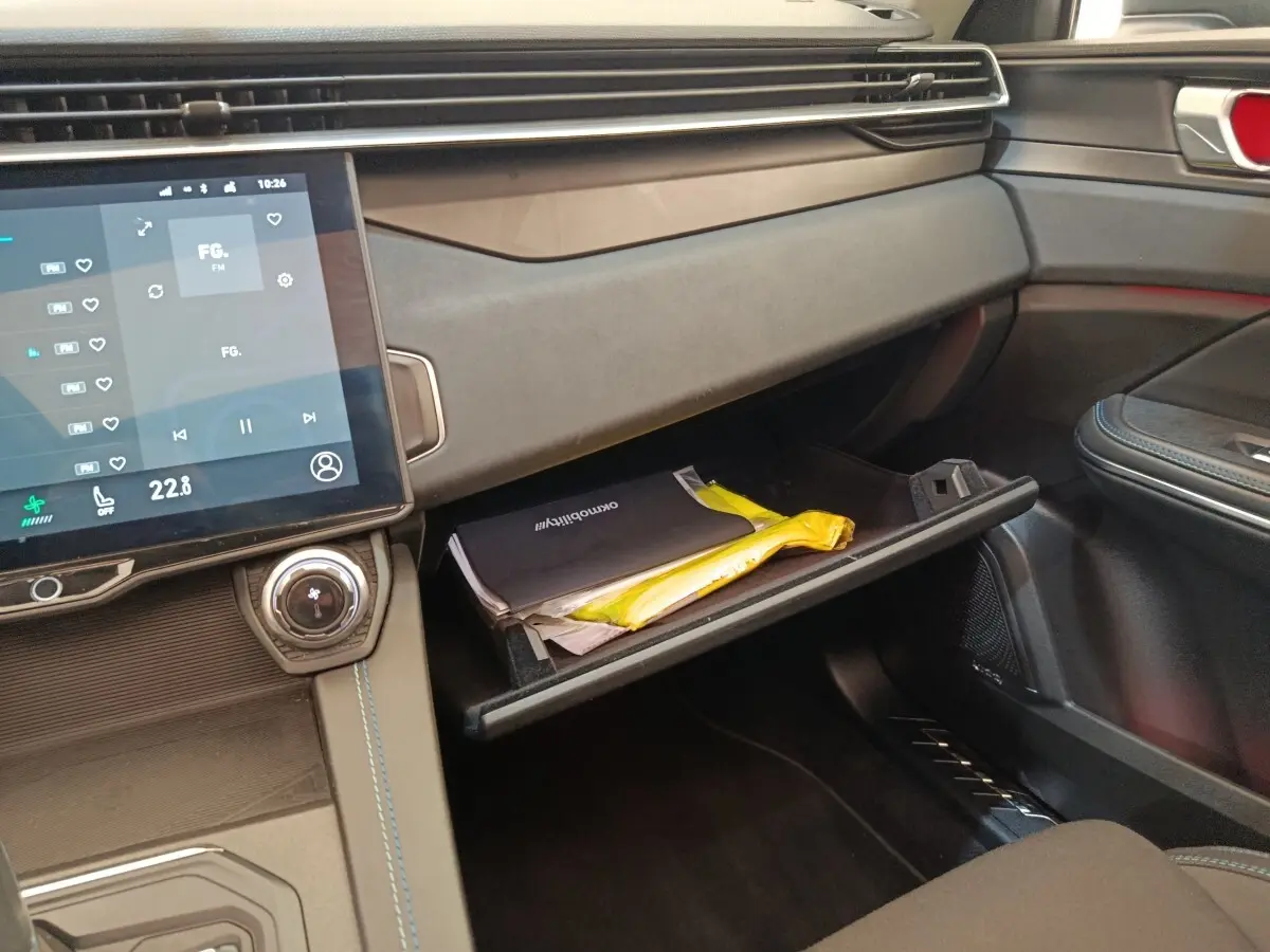 Intérieur du tableau de bord côté passager du Link & Co 01 hybride rechargeable 2022 avec boîte à gants ouverte et écran tactile central.
