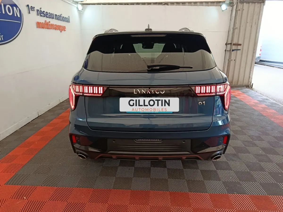 Vue arrière d'un SUV Lynk & Co 01 bleu avec feux LED distinctifs et double sortie d'échappement.