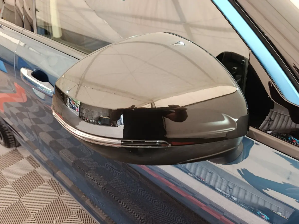 Gros plan sur le rétroviseur droit noir brillant du SUV bleu Link & Co 01 hybride rechargeable, reflet intérieur visible.