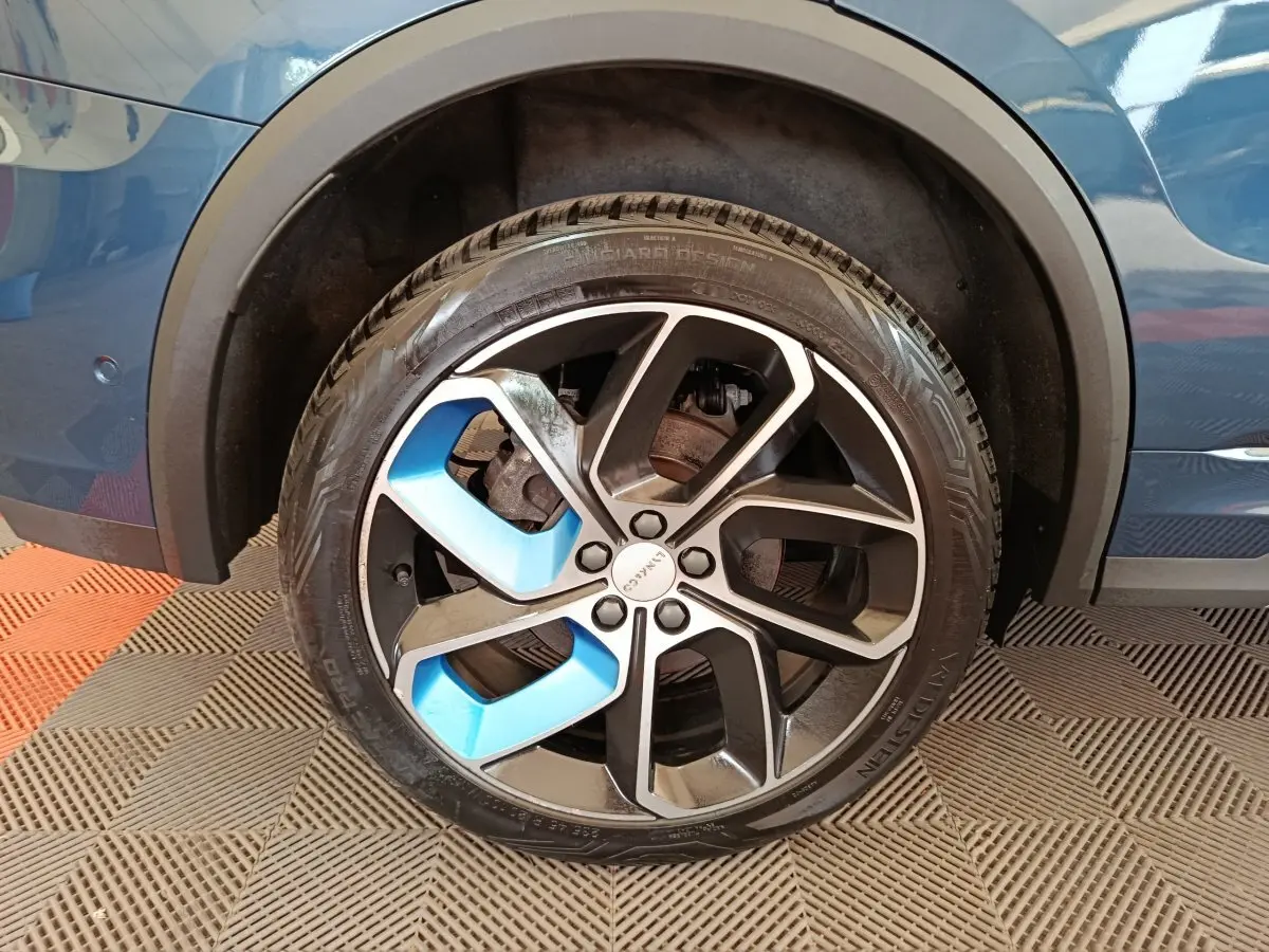 Gros plan sur la roue avant droite bleue du SUV Link & Co 01 hybride rechargeable 2022 avec jante noire et bleue.