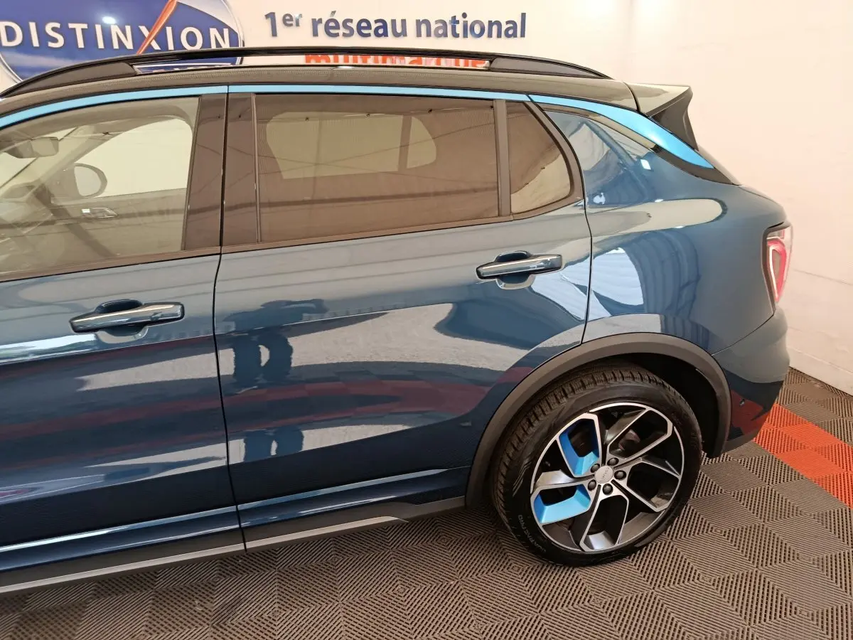 Vue latérale droite d'un SUV LINK & CO 01 hybride rechargeable bleu avec jantes noires et bleues, portes et vitres teintées.