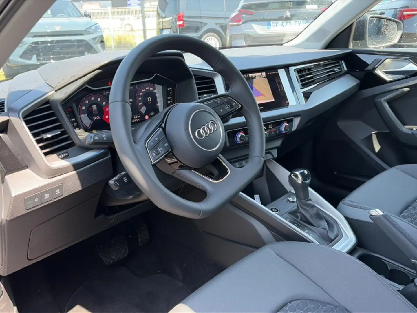 Vue intérieure côté conducteur de l'Audi A1 Sportback 30 TFSI 2026 avec volant cuir multifonction et console centrale moderne.