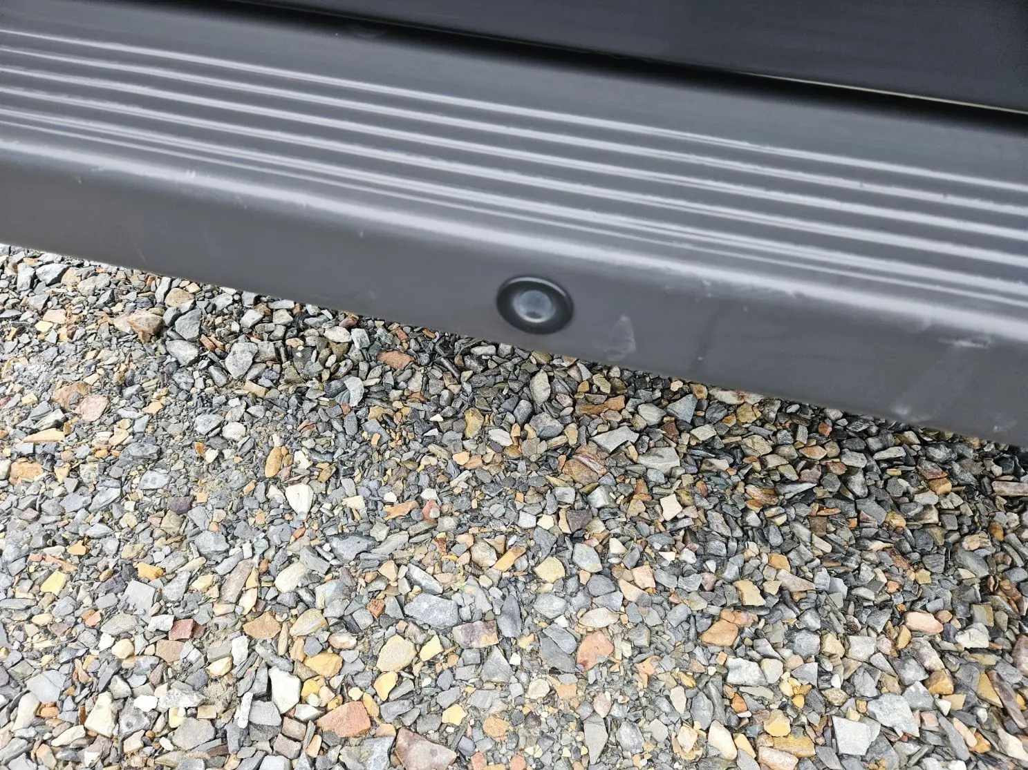 Gros plan sur le bas de caisse noir avec capteur de stationnement du Fiat Ducato Combi blanc, vue latérale basse.