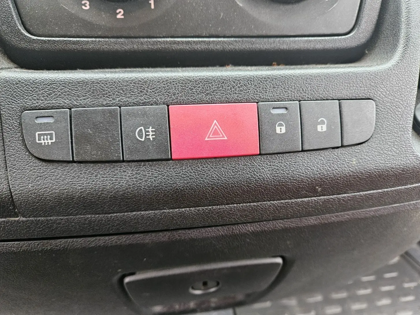 Gros plan sur les boutons de commande noirs et rouge du tableau de bord du Fiat Ducato Combi blanc 2014.