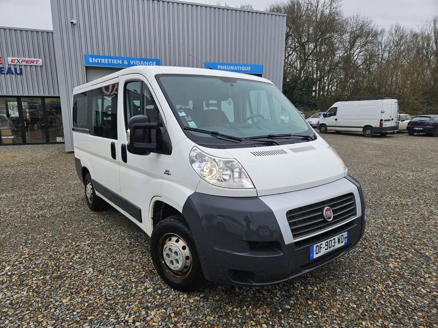 Fiat Ducato Combi blanc vu en 3/4 avant droit, avec pare-chocs noir et neuf places visibles à l'intérieur.