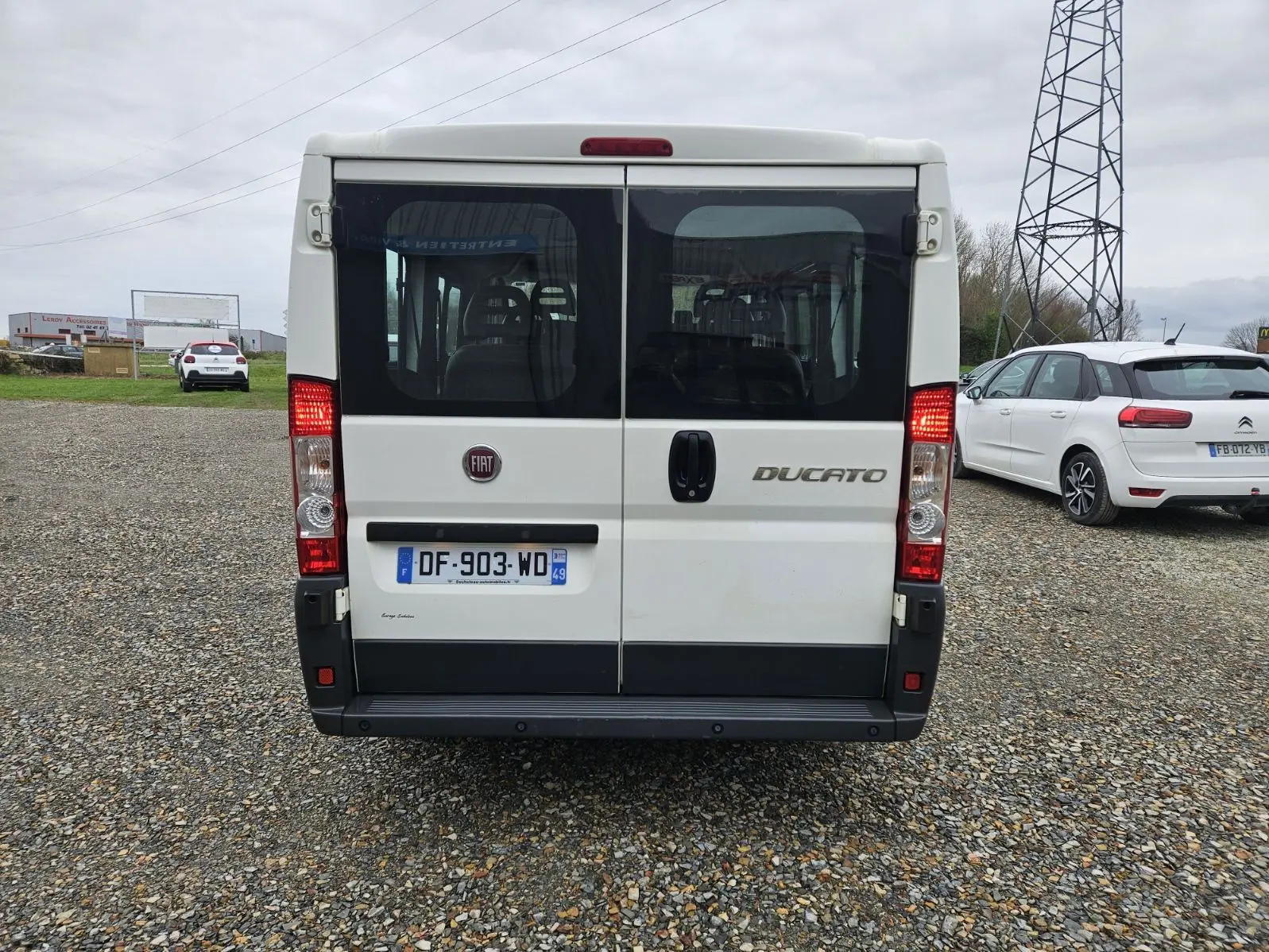 Vue arrière d'un FIAT Ducato Combi blanc 2014, version 9 places, avec portes vitrées et feux allumés.