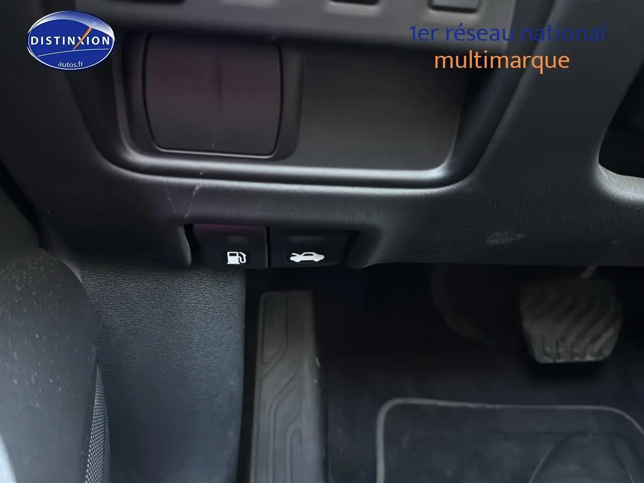 Détail des commandes d'ouverture du capot et de la trappe à carburant sous le tableau de bord côté gauche d'un Renault Koleos gris.