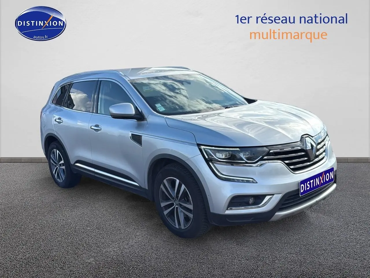 Renault Koleos gris en 3/4 avant droit avec jantes alu et calandre chromée sur fond neutre.