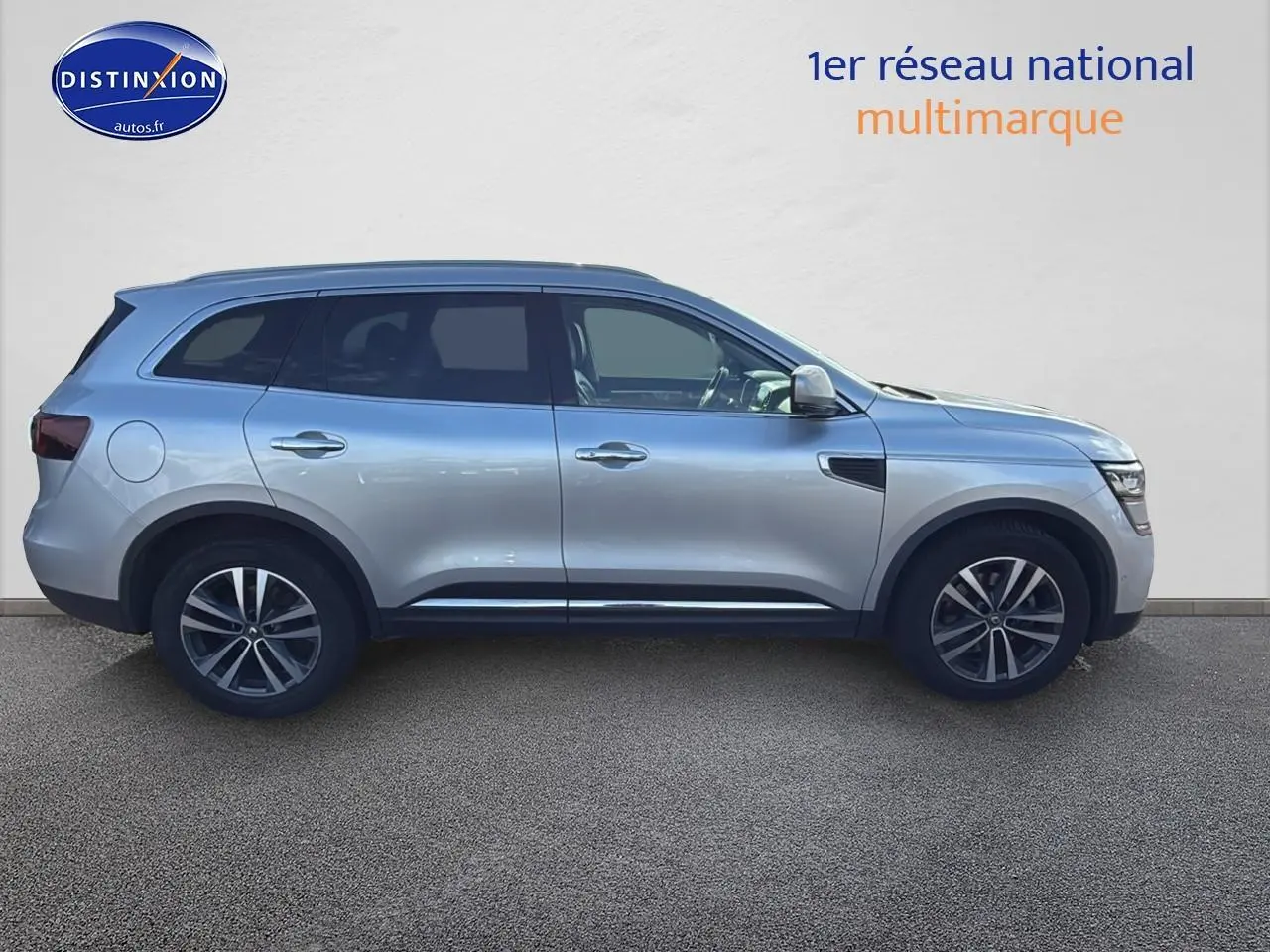 Profil côté gauche d'un Renault Koleos gris 2017 avec jantes alliage et barres de toit visibles.