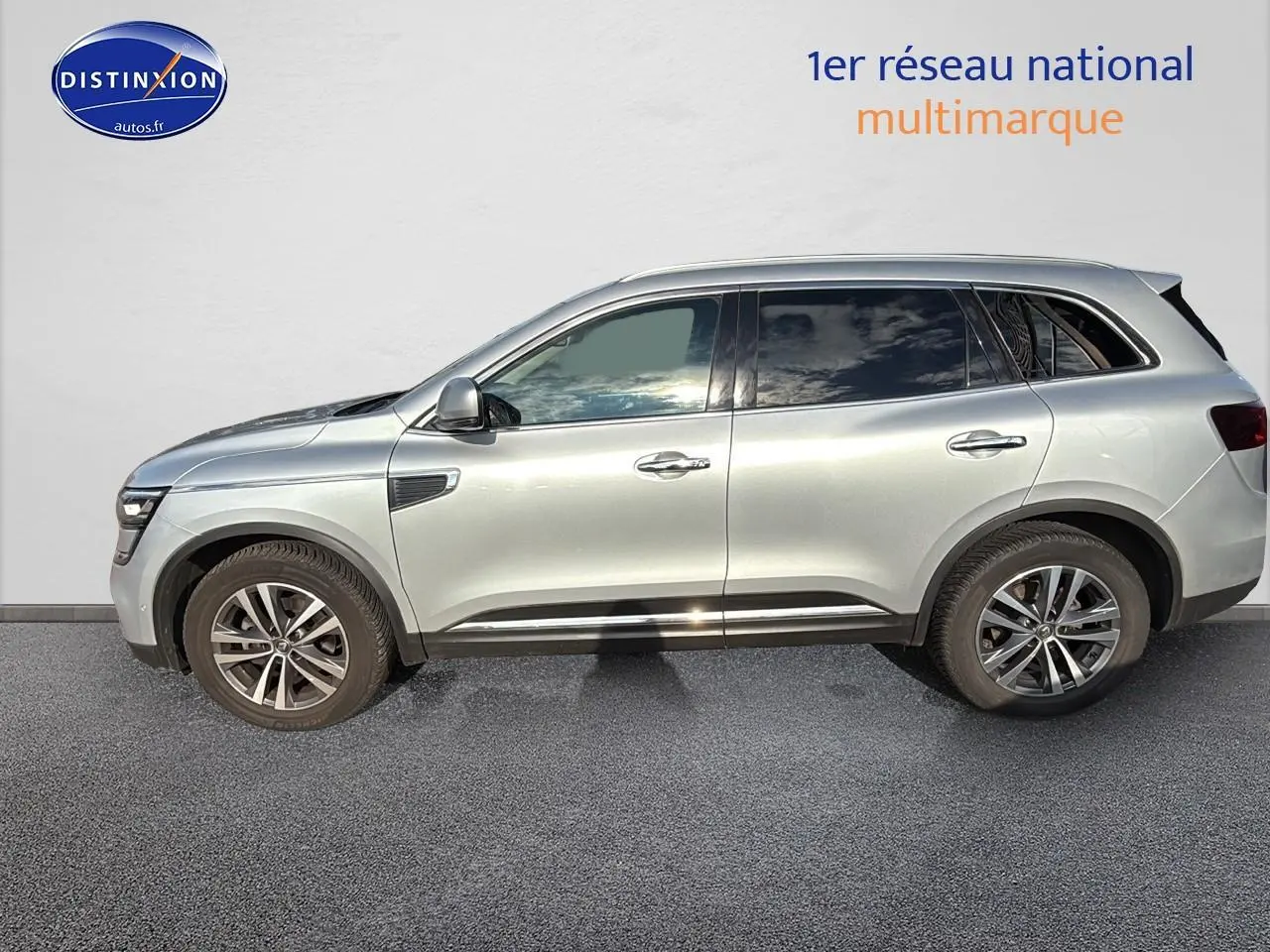 Profil côté gauche d'un Renault Koleos gris 2017 garé devant un mur blanc, avec jantes alliage visibles.