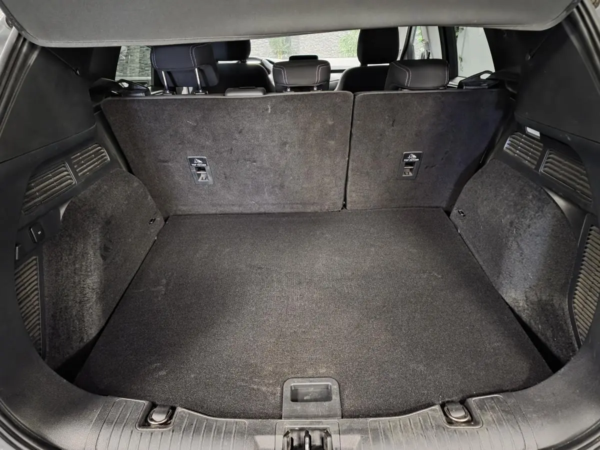 Coffre spacieux du Ford Kuga 2021 vu de l'arrière avec banquette arrière en tissu et tapis de sol noir.