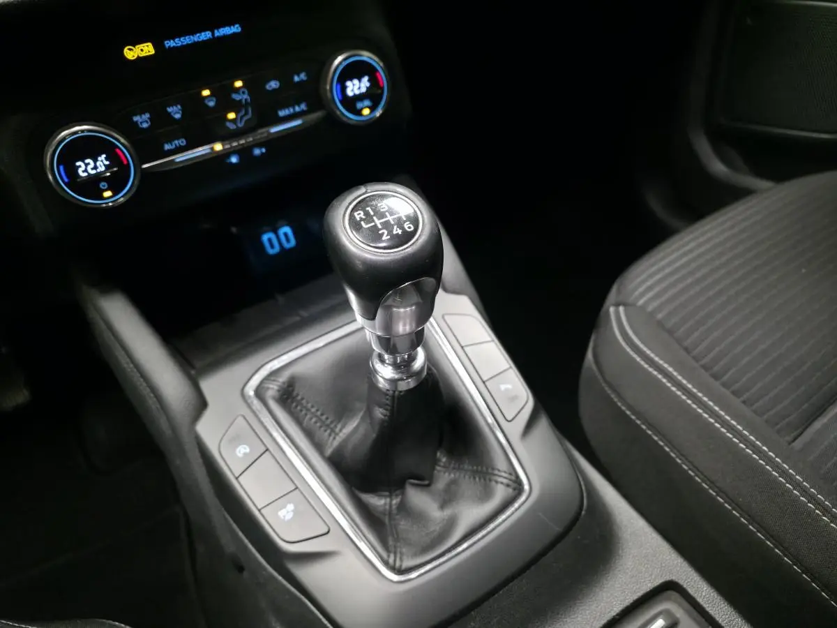 Levier de vitesses manuel noir en gros plan dans l'habitacle du Ford Kuga gris, avec console centrale et siège tissu visible.