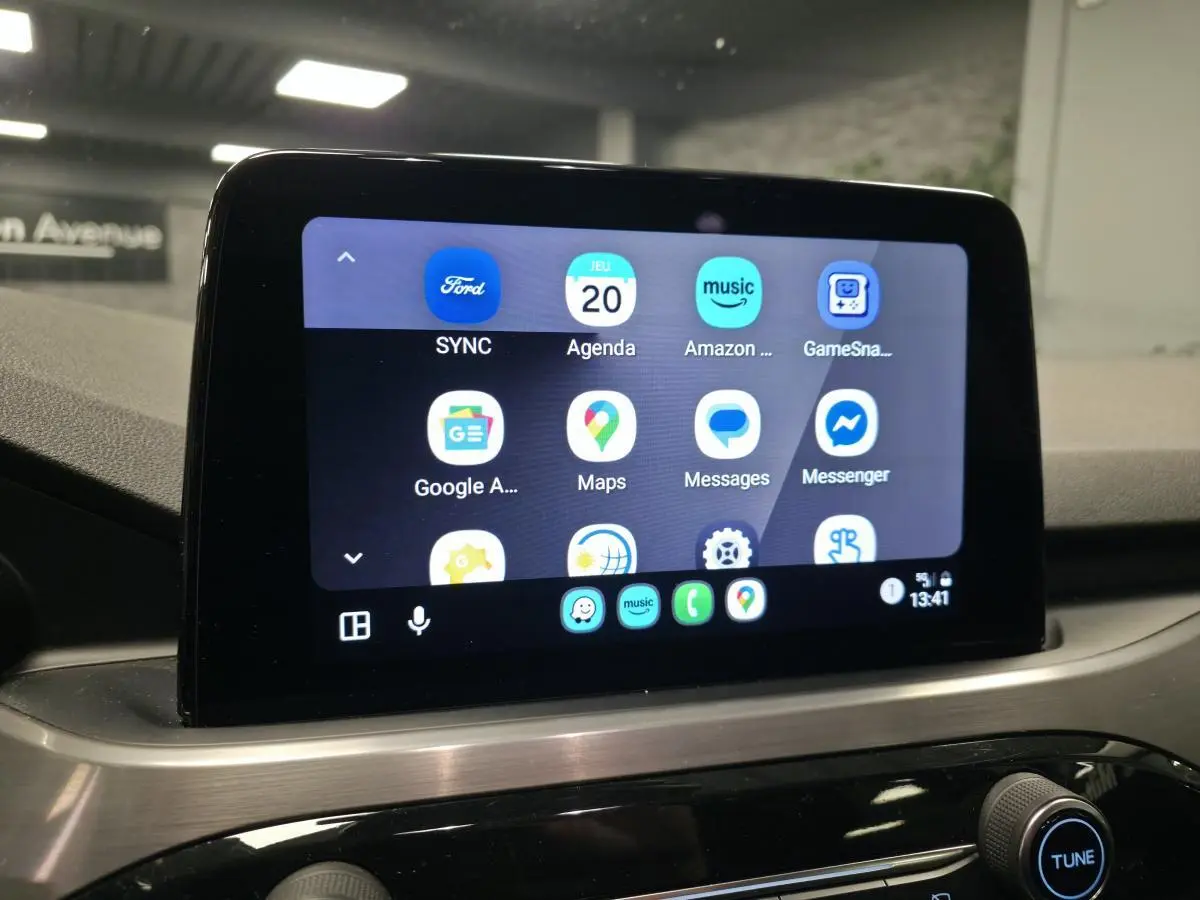 Écran tactile central du Ford Kuga 2021 affichant l'interface SYNC avec applications connectées, vue intérieure.
