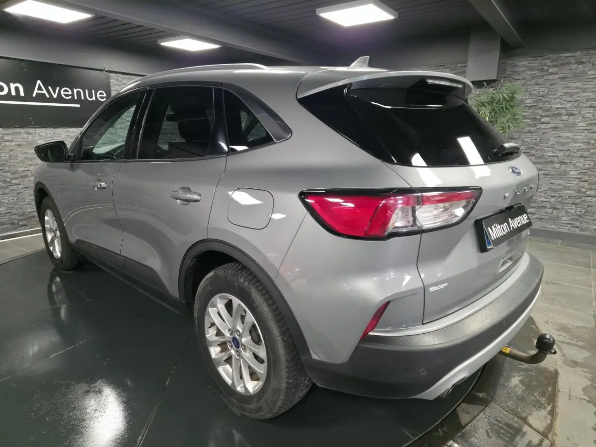 Vue 3/4 arrière droite du Ford Kuga gris métallisé avec crochet d'attelage et vitres arrière surteintées.