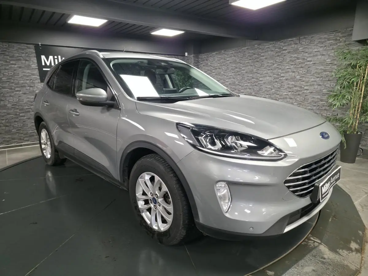Vue 3/4 avant droite d'un Ford Kuga gris métallisé avec calandre Titanium et jantes alliage 17 pouces.