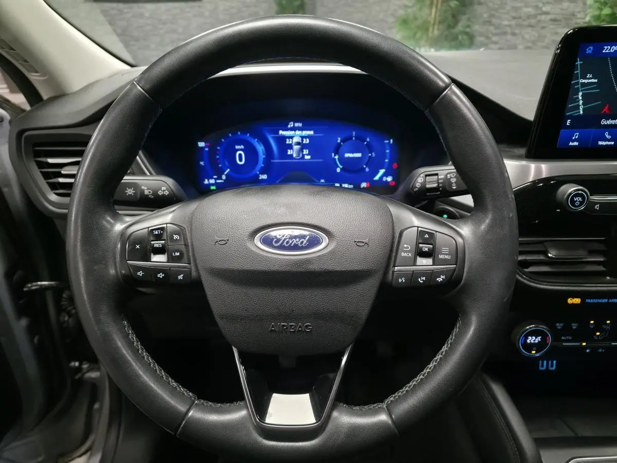 Vue rapprochée du volant noir en cuir du Ford Kuga 2021 avec tableau de bord numérique et écran tactile central.