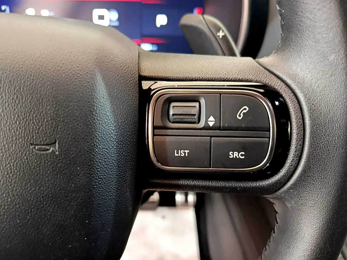 Gros plan sur les commandes gauche du volant noir du Citroën C5 Aircross 2023, boutons LIST et SRC visibles.