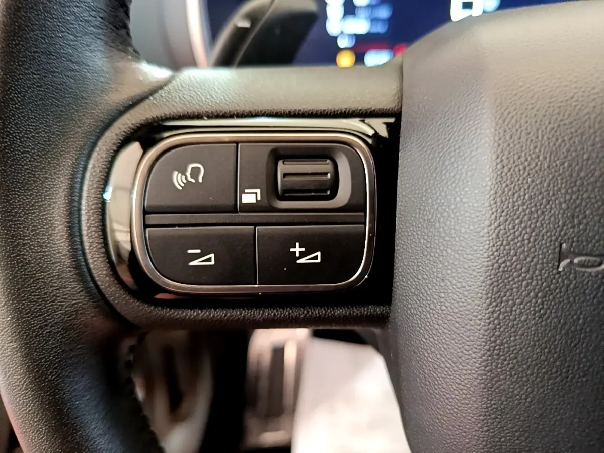 Gros plan sur les commandes multifonctions noires à gauche du volant cuir noir du Citroën C5 Aircross 2023.