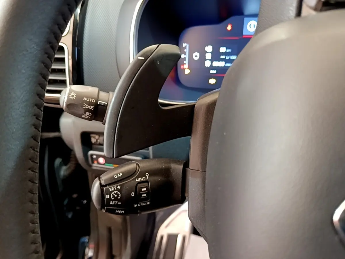 Gros plan sur la commande multifonction du volant côté gauche du Citroën C5 Aircross 2023, affichage digital en arrière-plan.