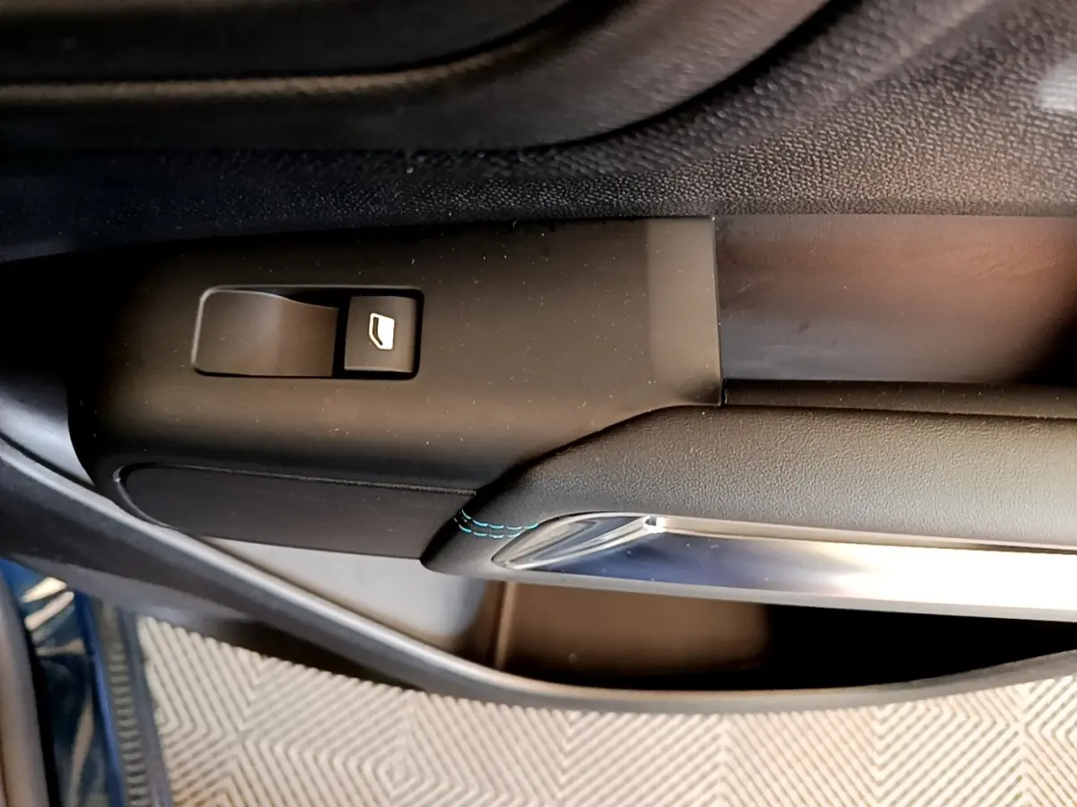 Gros plan sur la commande de lève-vitre côté conducteur du Citroën C5 Aircross 2023 avec surpiqûres bleues.