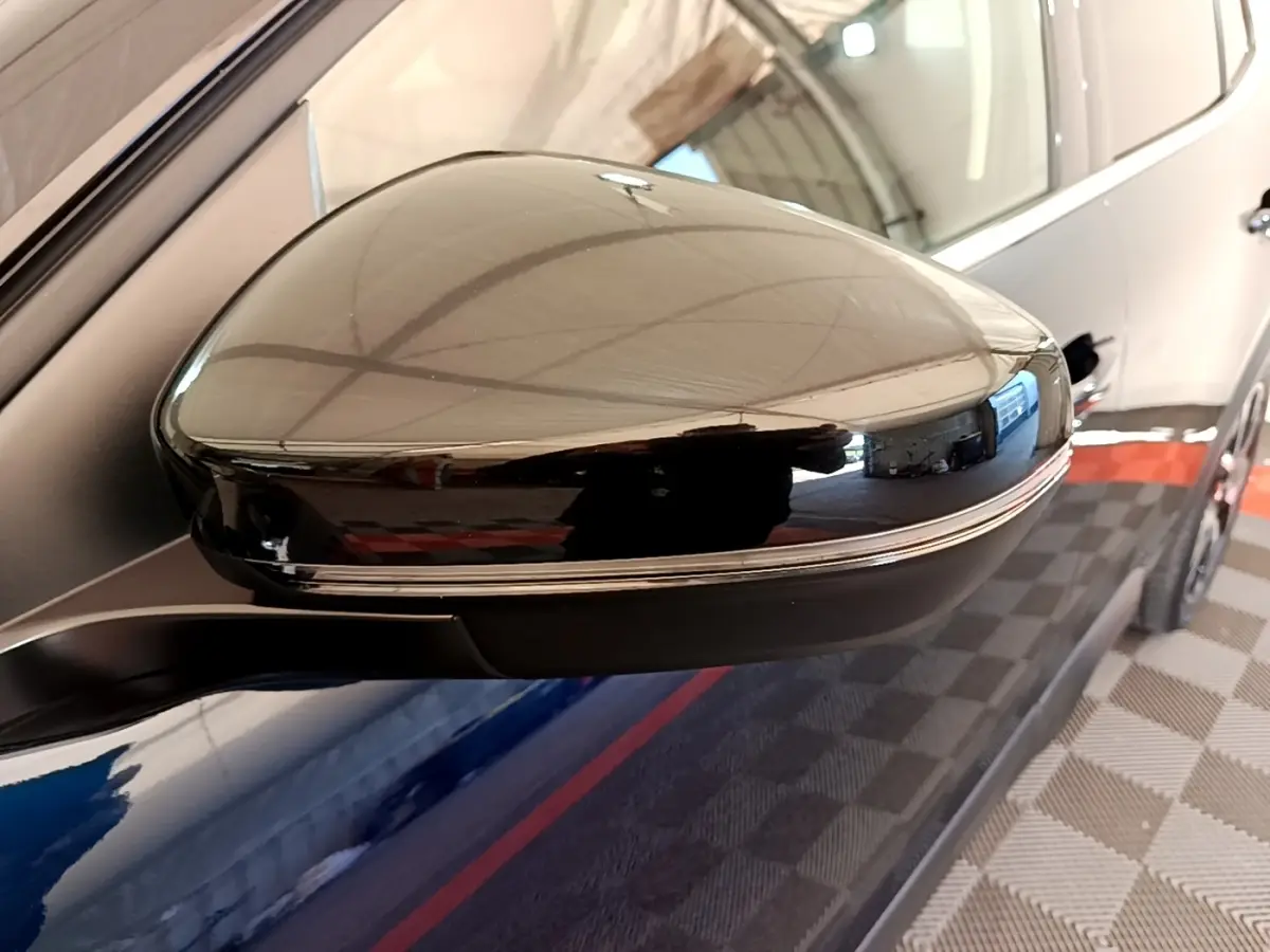 Gros plan sur le rétroviseur droit noir brillant du Citroën C5 Aircross 2023, avec reflet de l'environnement intérieur.