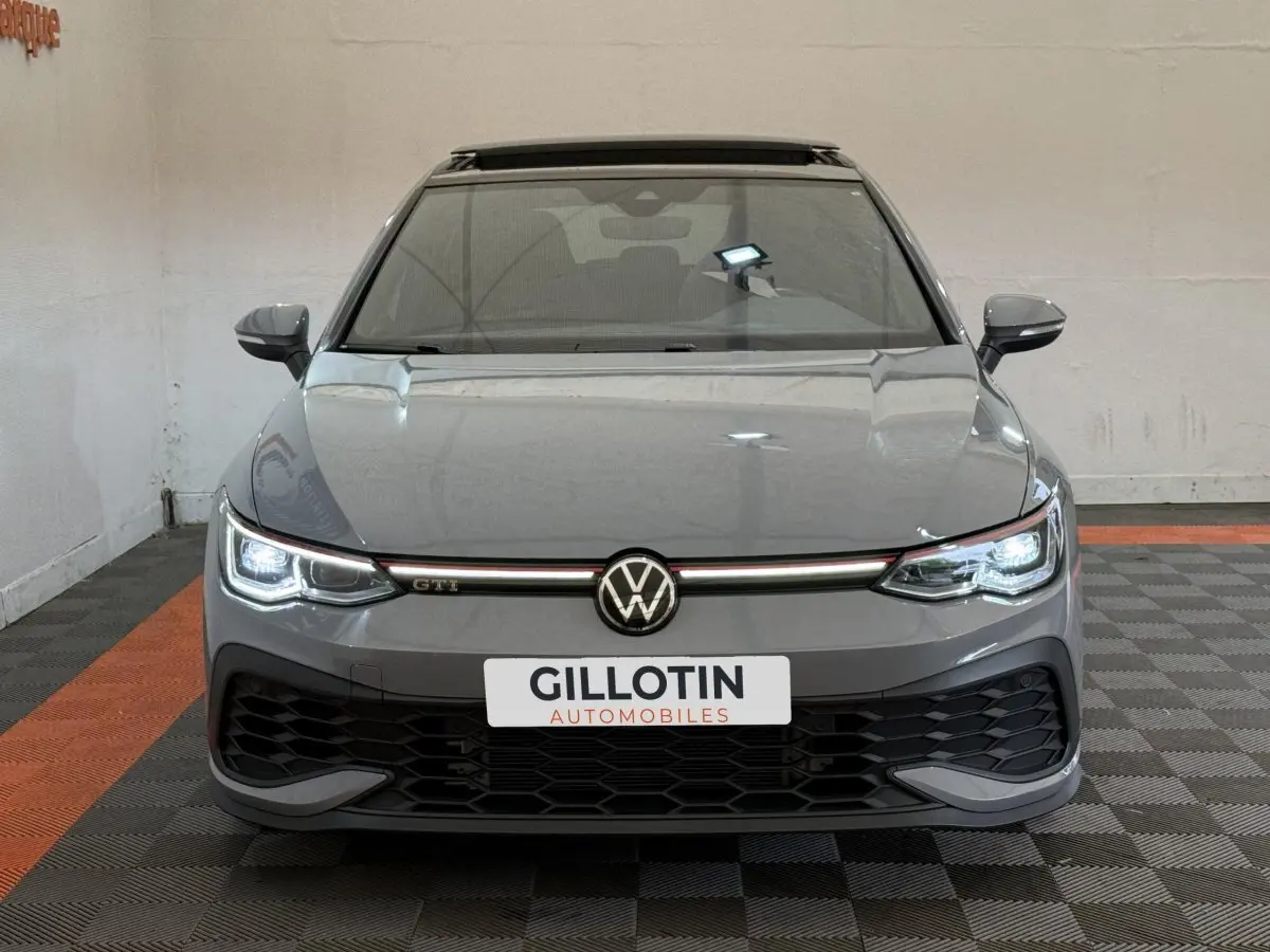 Vue frontale d'une Volkswagen Golf GTI Clubsport 2022 gris foncé avec phares LED allumés et calandre noire sportive.