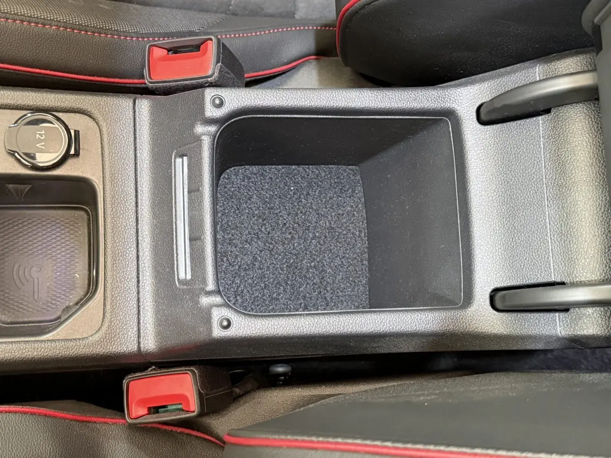 Vue plongeante sur la console centrale noire de la Volkswagen Golf GTI Clubsport 2022 avec surpiqûres rouges et prise 12V.